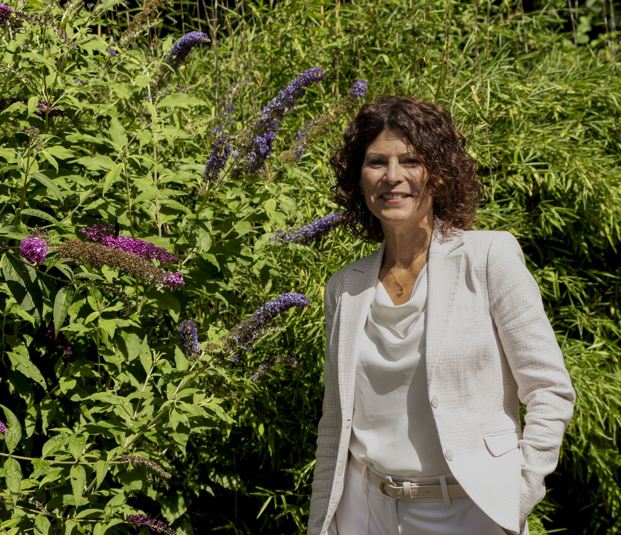 Jeanine, vertrouwenspersoon bij Confidence Talk, bij een bloeiende vlinderstruik